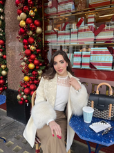 a lady wears a white knitted top with a white winter coat